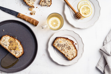 Slice of cake with walnuts and on plate and hot tea with lemon slice on white background, top view