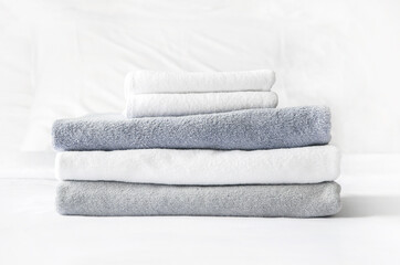 Fototapeta na wymiar folded terry towels lie on clean white bed. Cleaning in guest room of hotel, cleanliness, laundry
