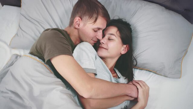 Happy young couple cuddling together in the bed. Realtime