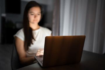 Casual beautiful woman working on a laptop at the night at home.