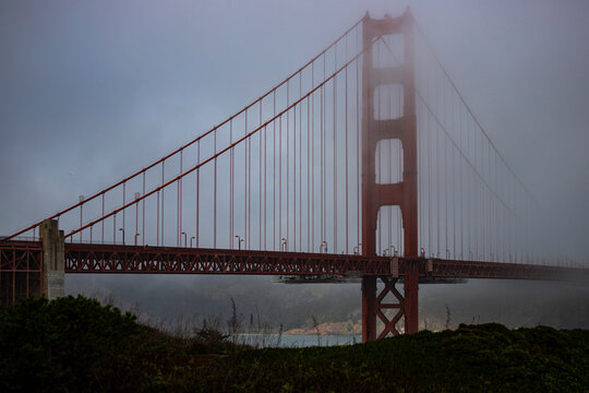 panorama of the golden gate bridge in san francisco during foggy weather; the famous red bridge emerging from behind the clouds, gloomy photo of the golden gate bridge