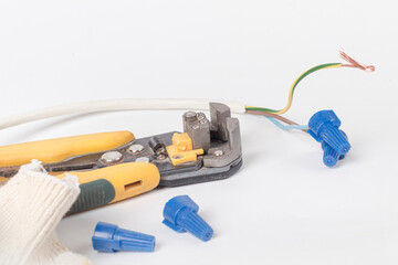 white background. electrical wires. the master removes the insulation with the help of a tool. close-up.