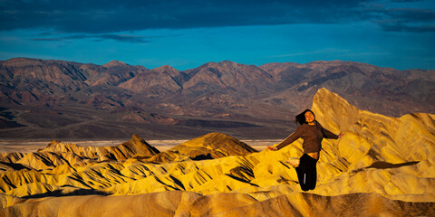 beautiful happy girl jumping for joy during sunrise in zabriskie point, death valley, california,...
