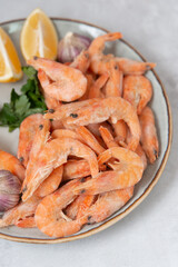 frozen raw shrimps with lemon and garlic on a gray rock  background 