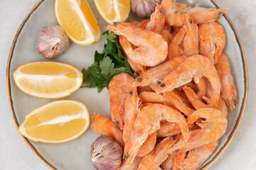 frozen raw shrimps with lemon and garlic on a gray rock  background 