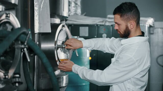 Technical brewer pouring beer from tank to check quality and consistency