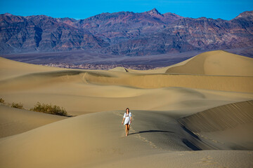 beautiful girl in lace dress lost in the middle of sandy desert; walking through mesquite flat sand...