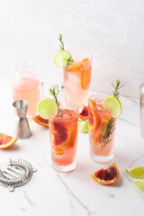 Cocktail with lime and blood red orange on a marble table, barmans tools and props. Summer...