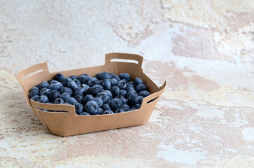 Fresh tasty blueberries in a cardboard container on an abstract background. Healthy food concept. Source of vitamins	