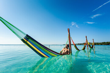 Man on hammock in Bacalar lagoon Mexico - 574405871