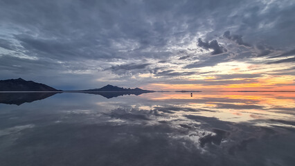 Fototapeta na wymiar Scenic view of beautiful water reflections in lake of Bonneville Salt Flats at sunrise, Wendover, Western Utah, USA, America. Dreamy clouds mirroring on the water surface creating romantic atmosphere