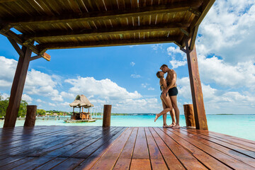Couple relaxing on a pier Bacalar lagoon Mexico - obrazy, fototapety, plakaty