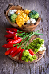 broccoli of various colors and fresh red hot chili peppers on the wooden cutting board