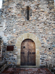 imagen de una puerta de madera en una fachada de piedra y el suelo de baldosas