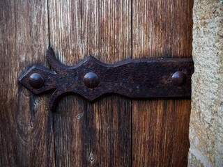 imagen detalle puerta de madera con los soportes y clavos de hierro oxidado