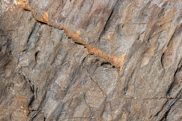 Textured rocky background is gray with orange spots. Rocky stone wall with orange patterns.