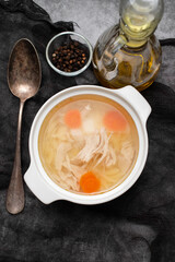 bowl of chicken broth with chicken and carrot in dark