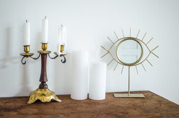 Vintage brass candelabra with white candles and eye mirror on dresser.