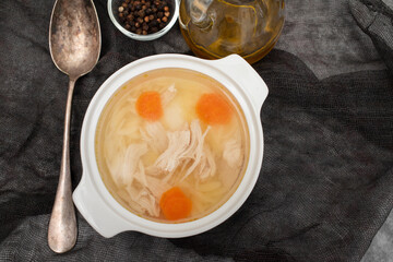 bowl of chicken broth with chicken and carrot in dark