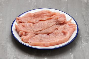 Slices of raw turkey meat fillet on white dish