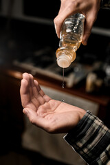 Close-up of male hand with bottle of oil for hair
