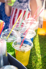 Multi-colored cold lemonade in a glass with a straw on the street in a bar.
