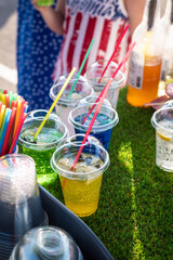 Multi-colored cold lemonade in a glass with a straw on the street in a bar.
