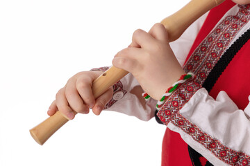 Bulgarian boy musician with flute in traditional folklore costume with martenitsa symbol of spring,...