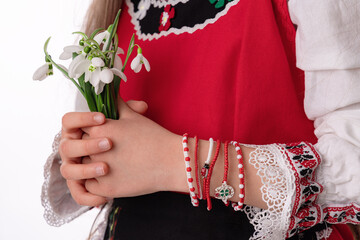 Bulgarian girl in traditional folklore costumes with spring flowers snowdrop and handcraft wool...