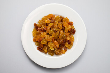Yellow golden raisins in white ceramic plate