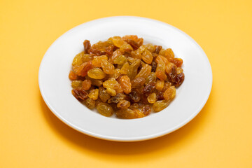 Yellow golden raisins in white ceramic plate