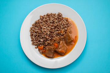 Boiled buckwheat with meat and sauce on white dish