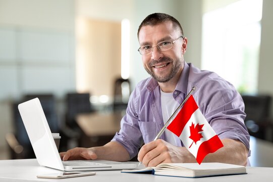 Young Business Man At Work With Flag Of Canada .