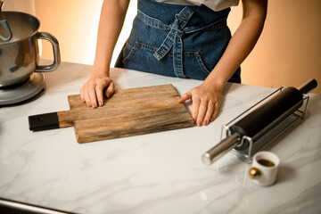 view on table with cutting board and rolling pin for dough and female hands