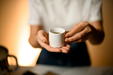 selective focus on small white cup with oil in female hands