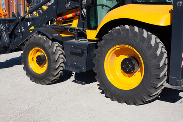 Rubber large black wheels with a raised surface. Car tread of road construction backhoe loader.