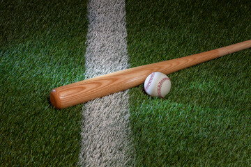 Fototapeta na wymiar Baseball and bat on grass field with white stripe