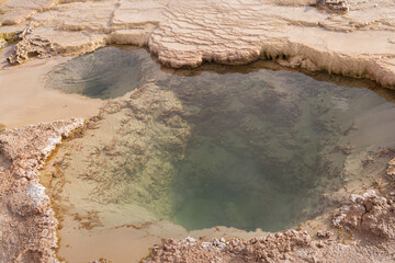 Close up of w hot spring in white travertine deposits at the El Tatio geyser field in the high...