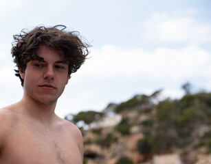 Portrait of a young man on holiday shirtless in front of the sky and forest