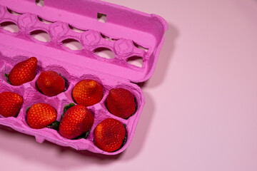 Pink Egg Carton with Ripe Strawberries on a Vibrant Pink Background