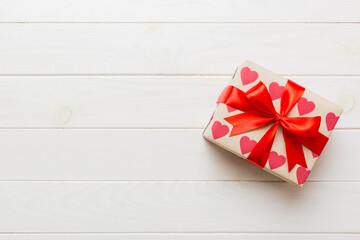 Top view photo of valentine day decorations gift box with red ribbon bow on colored background....