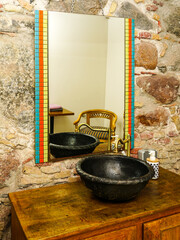 Vintage style bathroom interior with black round ceramic sink with brass faucet on top of cabinet