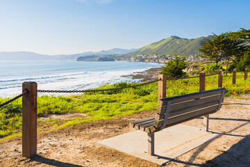Obraz premium Walkway along the shore and wooden bench overlooking the ocean, California