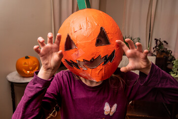 Child being silly and scary in DIY Halloween pumpkin mask