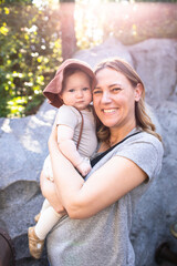 woman holding a baby with a sun hat in the park