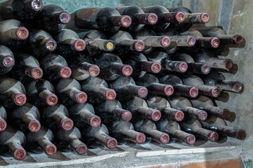 Dusty wine bottles are stored on a shelf