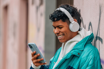 Fototapeta na wymiar young urban latino man with mobile phone and headphones in the street