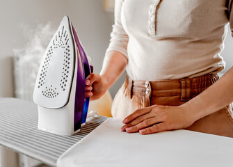 Girl hand using iron for wrinkled clothes