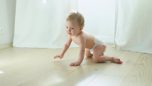 Smiling crawling cute baby in diaper at home on floor