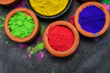 top view of colorful traditional holi powder in bowls isolated on dark background.Space for text . happy holi.Concept Indian color festival called Holi